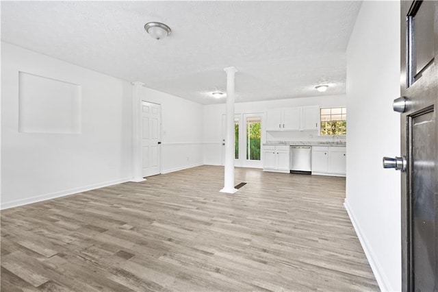 unfurnished living room featuring light hardwood / wood-style floors, sink, and a textured ceiling