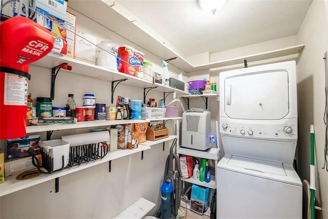 clothes washing area featuring stacked washing maching and dryer and laundry area