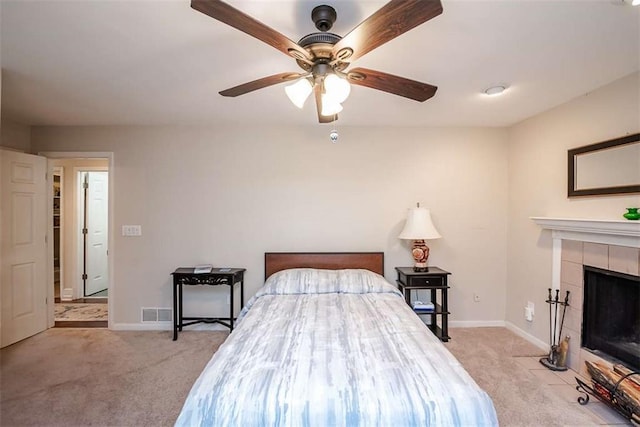 bedroom featuring a tile fireplace, light colored carpet, visible vents, and baseboards