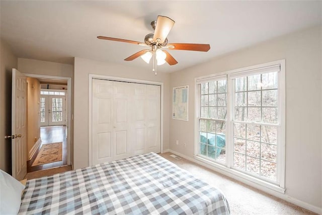 bedroom featuring ceiling fan, baseboards, a closet, and light colored carpet