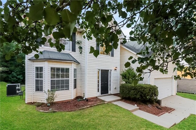 view of front of home featuring cooling unit, a garage, and a front lawn