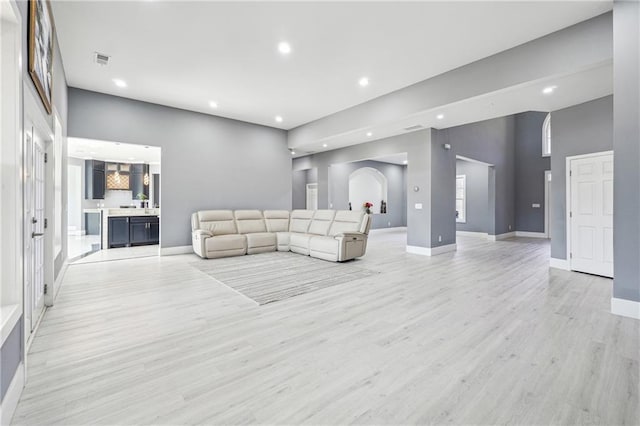 living area featuring recessed lighting, light wood-style flooring, baseboards, and a towering ceiling