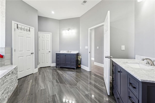 full bathroom with wood finished floors, baseboards, visible vents, two vanities, and a sink