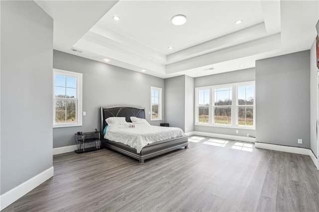 bedroom with recessed lighting, baseboards, a tray ceiling, and wood finished floors