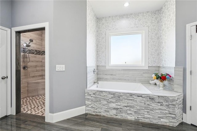 bathroom featuring baseboards, a bath, and a tile shower