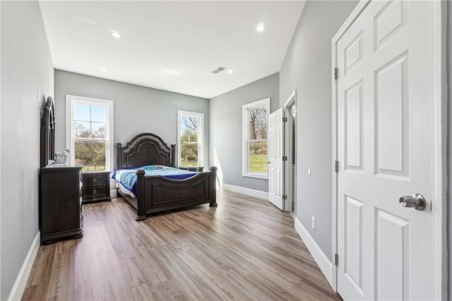 bedroom with visible vents, multiple windows, wood finished floors, and baseboards