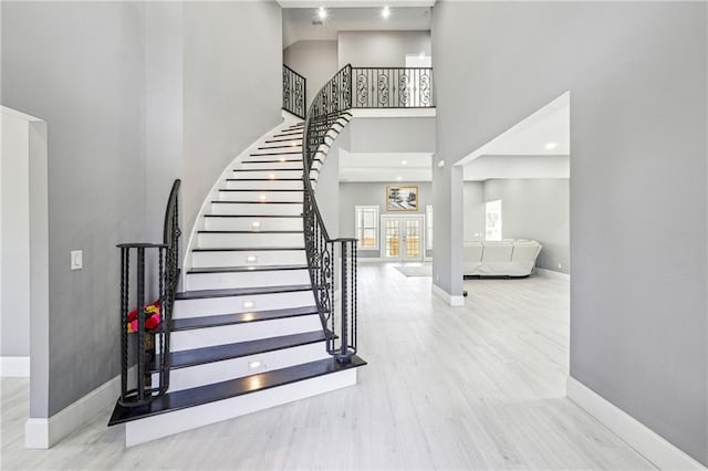 stairs featuring a towering ceiling, baseboards, and wood finished floors