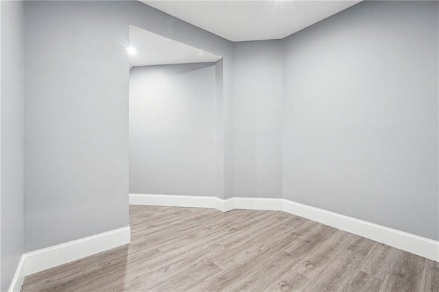 spare room with baseboards and wood finished floors