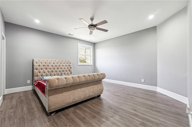 bedroom featuring visible vents, baseboards, wood finished floors, and a ceiling fan