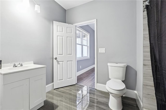 bathroom featuring vanity, toilet, and baseboards