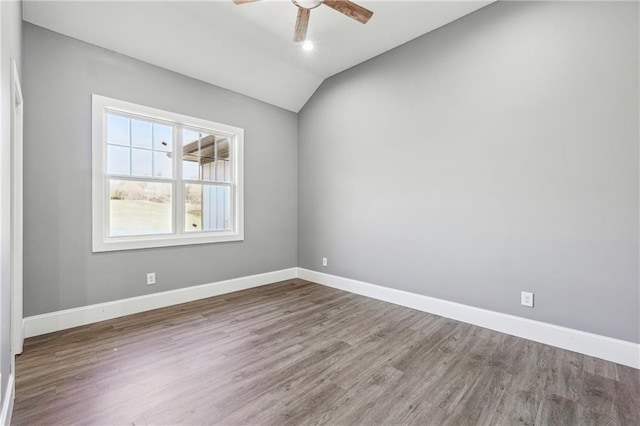 empty room featuring baseboards, wood finished floors, ceiling fan, and vaulted ceiling