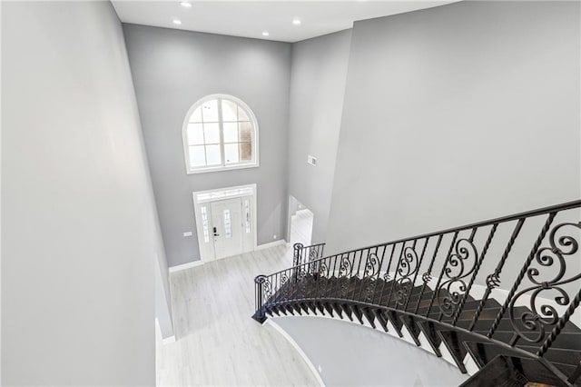 foyer entrance with baseboards, stairway, recessed lighting, a towering ceiling, and wood finished floors