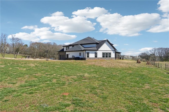 rear view of property with a yard, board and batten siding, and an attached garage