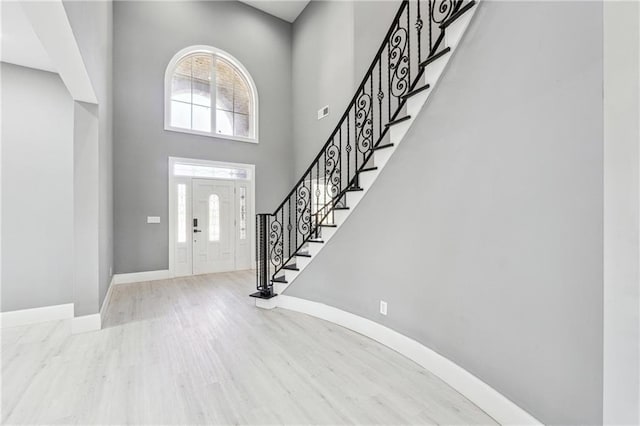 foyer entrance featuring stairs, wood finished floors, a healthy amount of sunlight, and baseboards