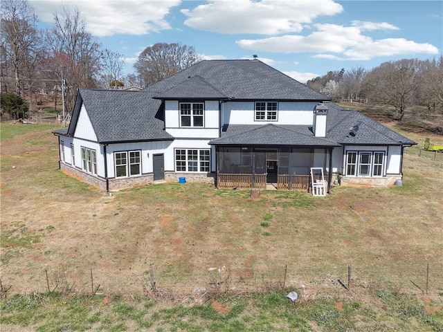 back of house with a yard, a sunroom, and roof with shingles