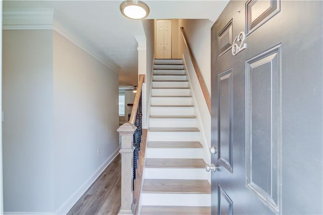 staircase with ornamental molding and hardwood / wood-style floors