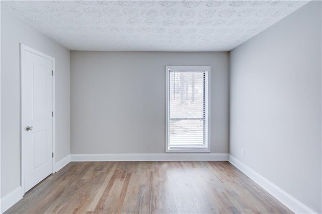 unfurnished room with light hardwood / wood-style flooring and a textured ceiling