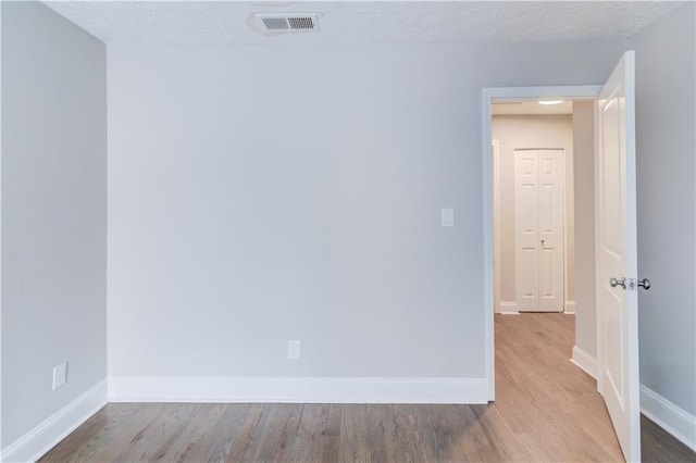 empty room with a textured ceiling and light hardwood / wood-style floors