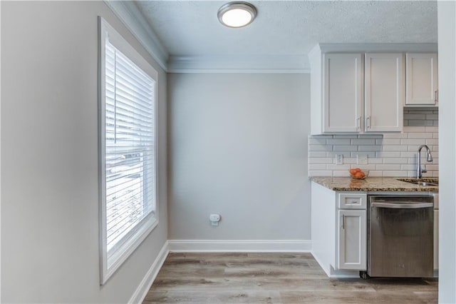 kitchen featuring sink, tasteful backsplash, stainless steel dishwasher, light stone countertops, and white cabinets