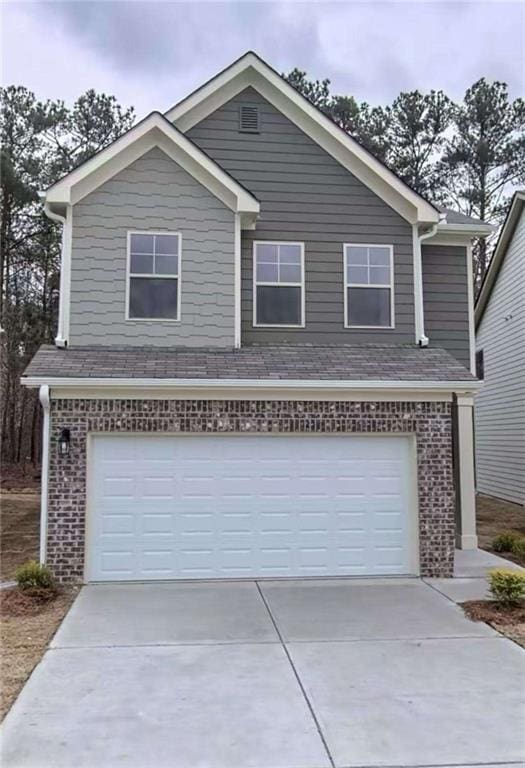 traditional-style home featuring an attached garage, brick siding, driveway, and a shingled roof