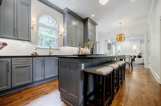 663 Clifton Rd NE, Atlanta, GA 30307 - kitchen featuring gray cabinets, crown molding, a kitchen breakfast bar, decorative backsplash, and dark wood-type flooring