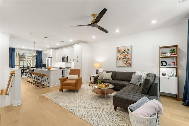 living room with ceiling fan, sink, and light hardwood / wood-style floors