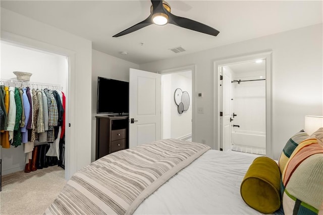 carpeted bedroom with ensuite bathroom, a spacious closet, a closet, and ceiling fan