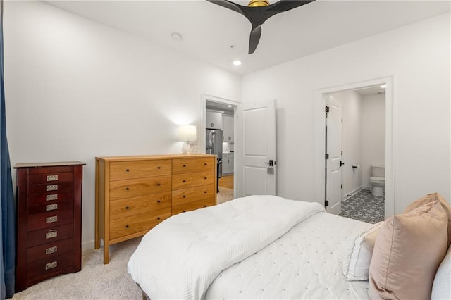 carpeted bedroom with ensuite bath, ceiling fan, and stainless steel refrigerator