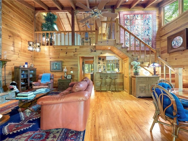 living room featuring wooden walls, ceiling fan with notable chandelier, and light wood-type flooring