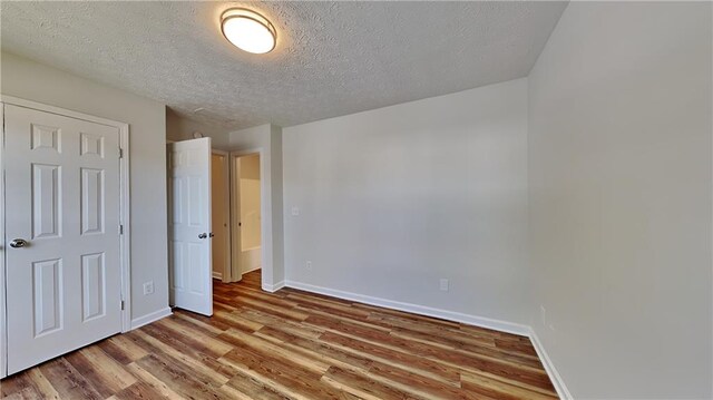 145 Charleston Pl, Covington, GA 30016 - unfurnished bedroom with baseboards, wood finished floors, and a textured ceiling