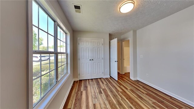 145 Charleston Pl, Covington, GA 30016 - unfurnished bedroom with wood finished floors, visible vents, a closet, baseboards, and a textured ceiling