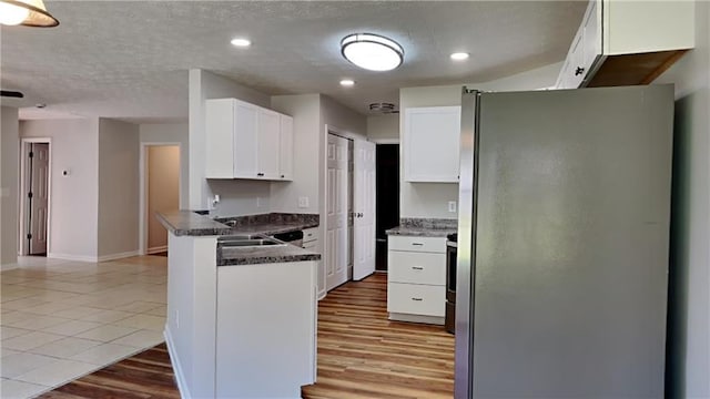 145 Charleston Pl, Covington, GA 30016 - kitchen featuring dark countertops, baseboards, a peninsula, white cabinetry, and freestanding refrigerator