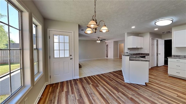 145 Charleston Pl, Covington, GA 30016 - kitchen featuring white cabinets, a textured ceiling, dark countertops, baseboards, and a chandelier
