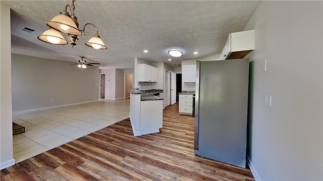 145 Charleston Pl, Covington, GA 30016 - kitchen with dark countertops, a textured ceiling, white cabinets, visible vents, and freestanding refrigerator