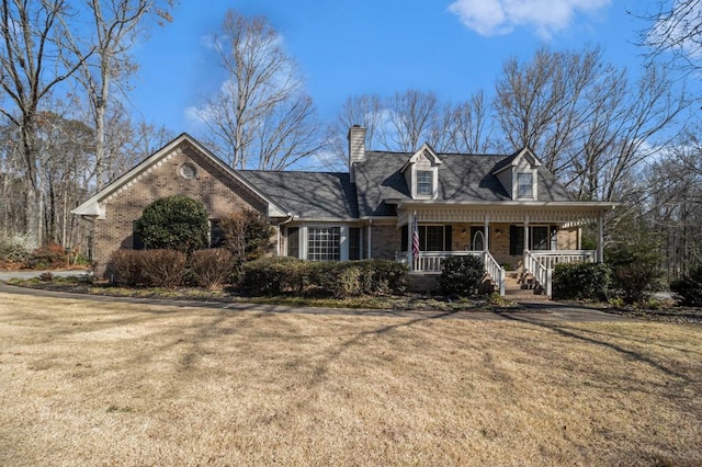 cape cod home featuring a front yard, a porch, and brick siding