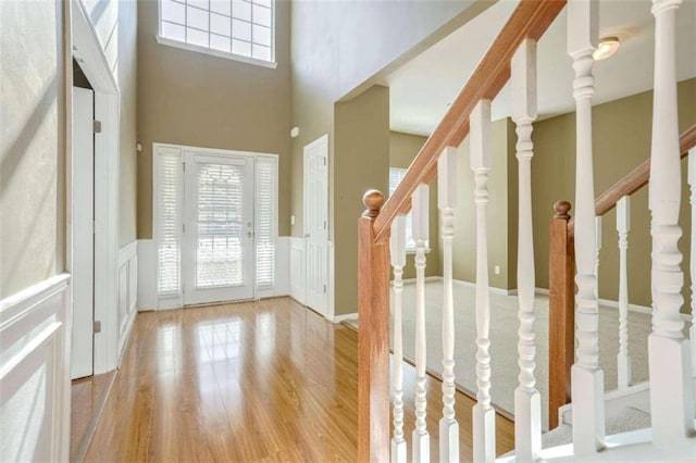 foyer with a towering ceiling, light hardwood / wood-style flooring, and a healthy amount of sunlight