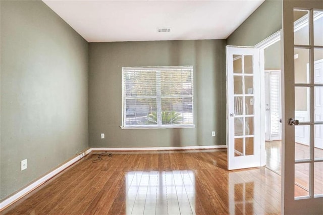 spare room featuring french doors and light wood-type flooring