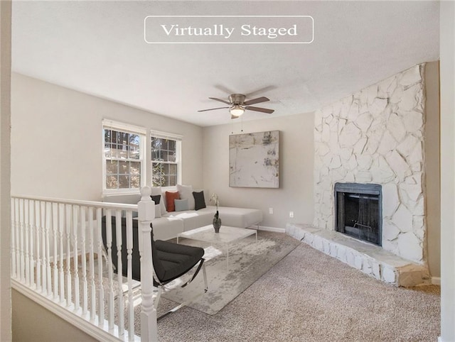 living room featuring carpet flooring, a stone fireplace, and ceiling fan