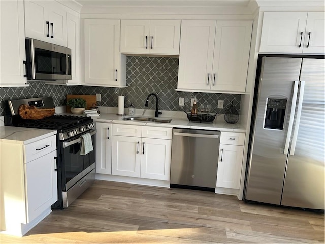 kitchen with a sink, stainless steel appliances, white cabinetry, and light countertops