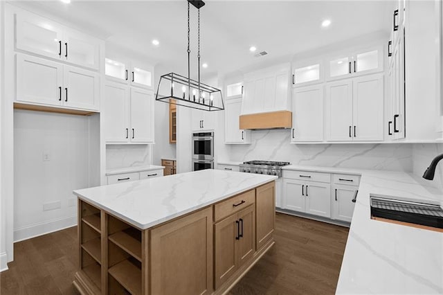 kitchen featuring a kitchen island, light stone countertops, glass insert cabinets, stainless steel appliances, and dark wood-type flooring