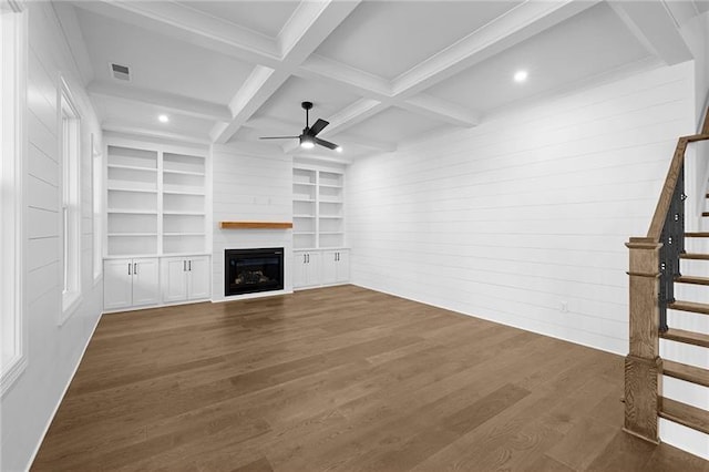 unfurnished living room featuring ceiling fan, a glass covered fireplace, stairs, dark wood-type flooring, and visible vents
