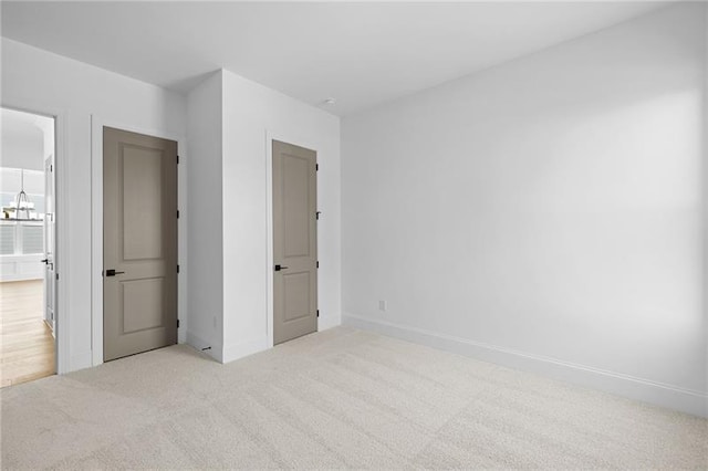 unfurnished bedroom featuring an inviting chandelier, baseboards, and carpet