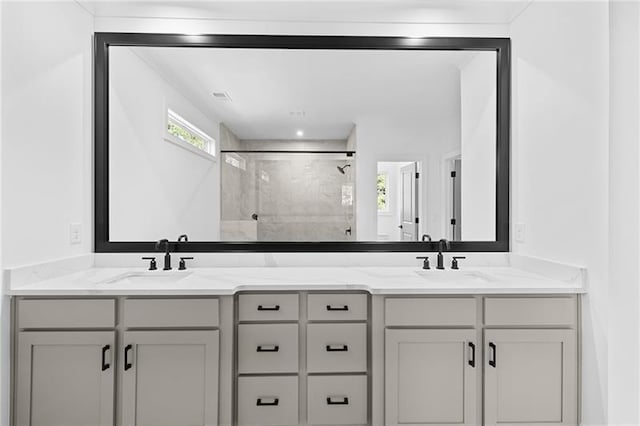 bathroom featuring a sink, a stall shower, and double vanity