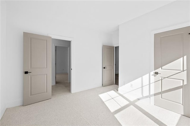 unfurnished bedroom featuring baseboards and light carpet