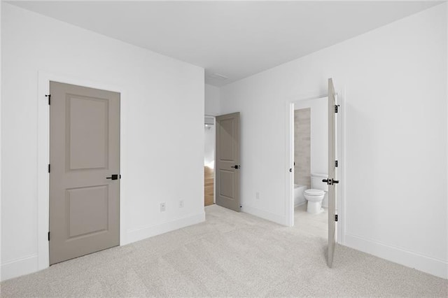 unfurnished bedroom featuring baseboards, ensuite bath, and light carpet