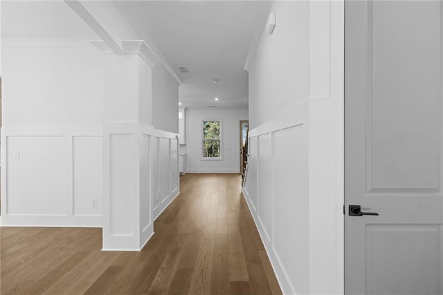 hallway with dark wood finished floors, wainscoting, visible vents, and a decorative wall
