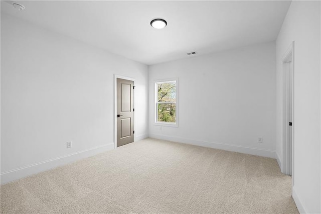 spare room with light colored carpet, baseboards, and visible vents