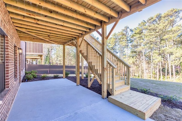 view of patio featuring fence and stairway