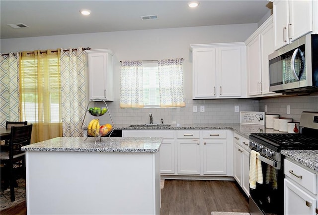 735 Sweethaven Ln, Loganville, GA 30052 - kitchen with stainless steel appliances, a sink, dark wood-style flooring, white cabinets, and a center island