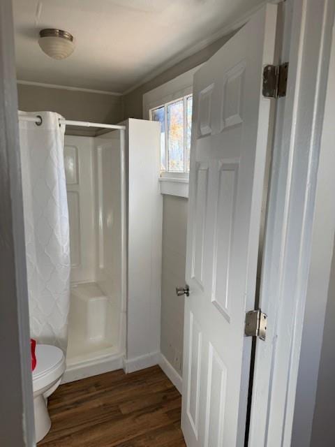 bathroom with hardwood / wood-style floors, toilet, a shower, and crown molding